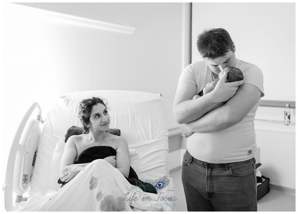 dad-holding-his-new-baby-for-the-first-time-while-mum-looks-on-life-in