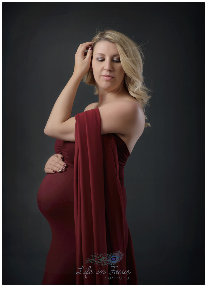 https://www.lifeinfocusportraits.co.uk/wp-content/uploads/2020/04/Maternity-photo-pregant-mum-to-be-in-red-dress-bump-photoshoot-Life-in-Focus-Portraits-photography-studio-Rhu-Helensburgh-1.jpg
