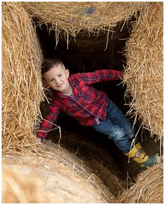boy playing in haybales on farm Life in Focus Portraits child photographer Luss Loch Lomond