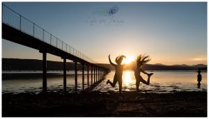 silhouette photo of friends leaping into air at sunset by lochside pier Life in Focus Portraits outdoor child photos Rhu Garelochhead Rosneath Cove