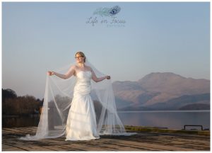 wedding photo bride holding veil on Luss pier in front of Ben Lomond Life in Focus Portraits wedding photography Lodge on Loch Lomond