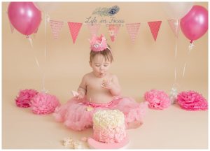 baby girl enjoying 1st birthday cake smash photo session Life in Focus Portriats studio Rhu Helensburgh