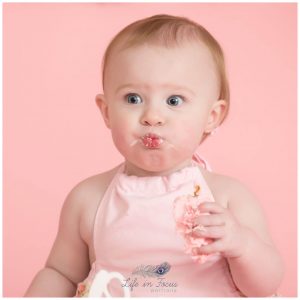 baby girl pulling cute face while eating 1st birthday cake Life in Focus Portriats baby photographer Rhu Helensburgh Cardross