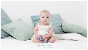 baby sitting on bed holding dummy Life in Focus Portraits little sitter baby milestone photoshoot Rhu Garelochhead Rosneath