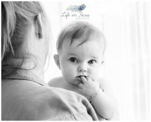 black and white photo of baby looking over Mum's shoulder Life in Focus Portraits baby photography Helensburgh Cardross