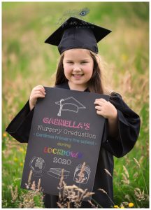 photo of little girl in nursery graduation cap and gown holding chalboard Life in Focus Portraits preschool graduation photos Helensburgh