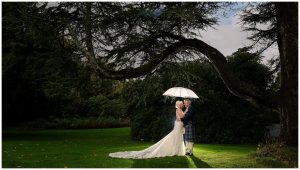 Bride and Groom embrace under umbrella Helensburgh Elopement Wedding