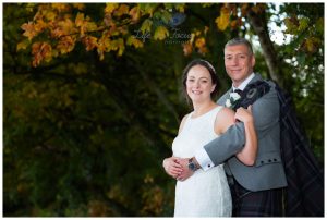 bride and groom wedding photo under autumn trees by Loch Lomond Luss