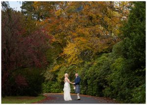 weddingphotograph os bride and groom hand in hand under autumn trees Rhu Helensburgh Argyll and Bute