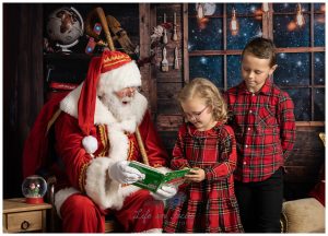 photo of boy and girl dressed in red tartan reading a book with Santa Life in Focus Portraits Christmas photoshoots Alexandria