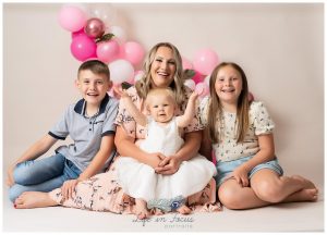 photo of Mum with children celebrating baby's 1st birthday with pink balloon arch Rhu photography studio